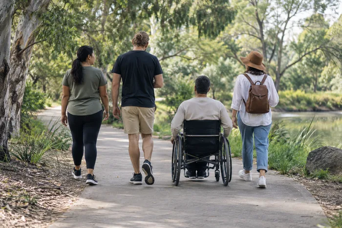 A small group, including a participant using a wheelchair, walking together on an outing