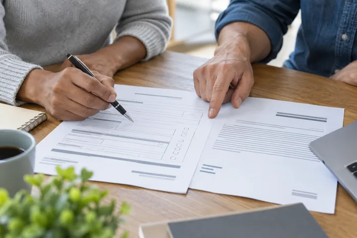 Two people reviewing a form together, close-up on hands